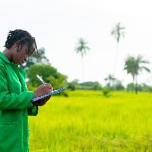 An African female farmer taking notes on a farm